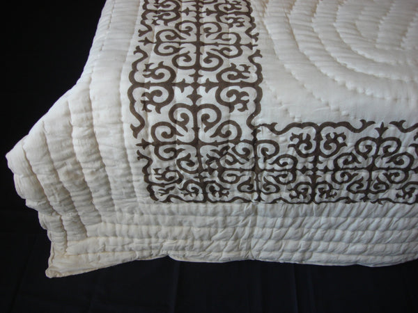 Handmade, patchwork cotton quilt in sequentially placed blocks with black designs on the reverse side