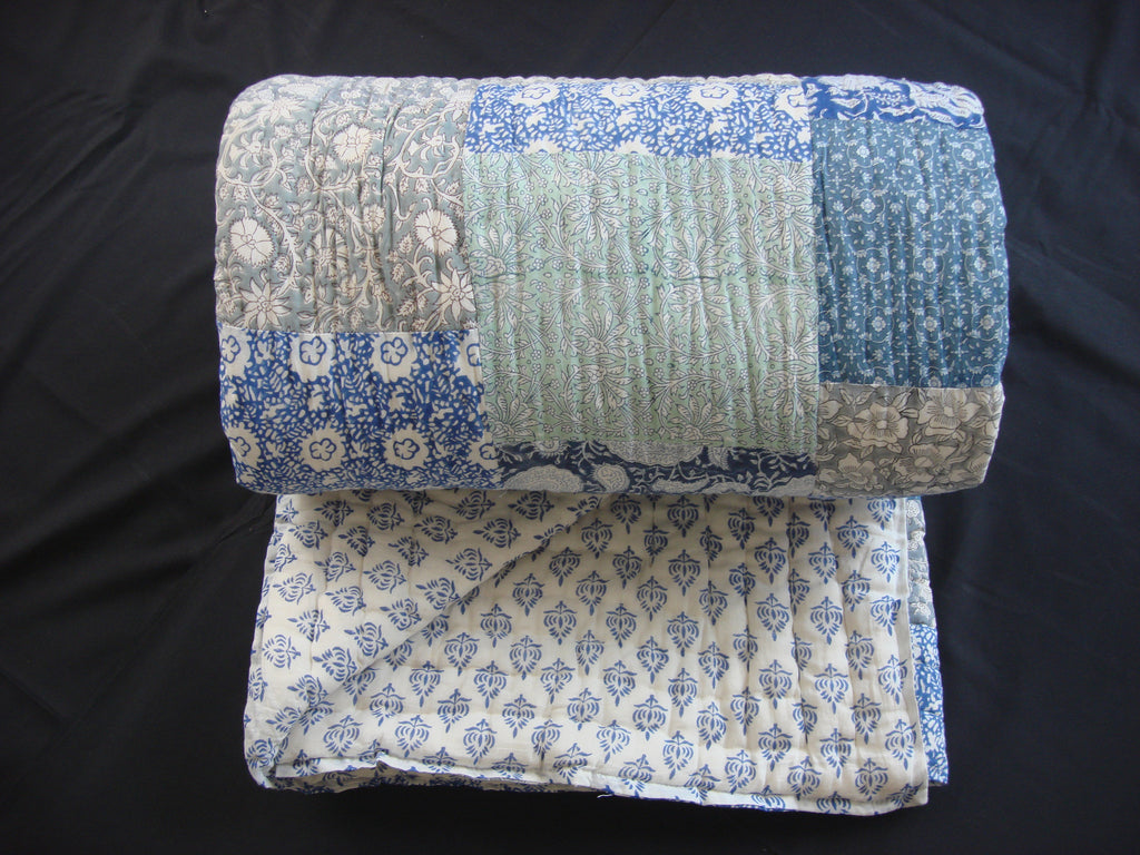 Handmade, patchwork cotton quilt in block printed blocks scattered in shades of grey and blue.