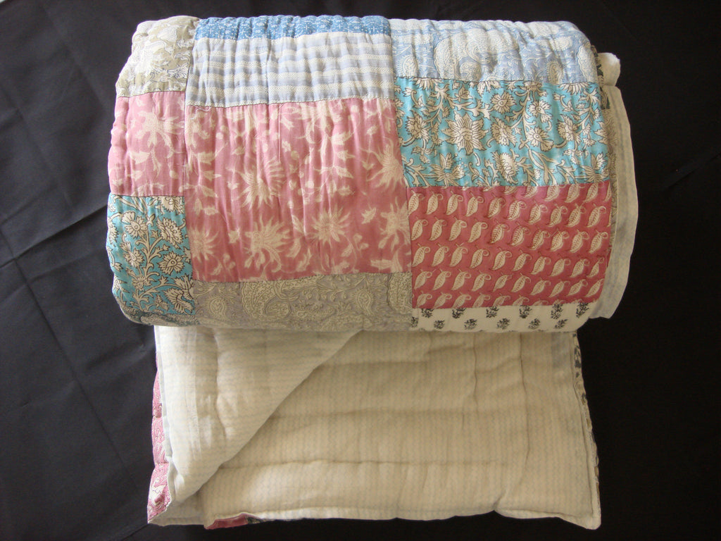 Handmade, patchwork cotton quilt in prints in shades of pink and blue